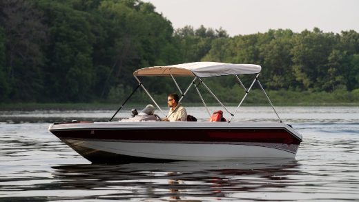 A man boating with a Bimini Top installed on his boat, enjoying sun protection and comfort