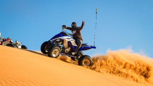 A man wearing goggles riding ATV in the desert-1