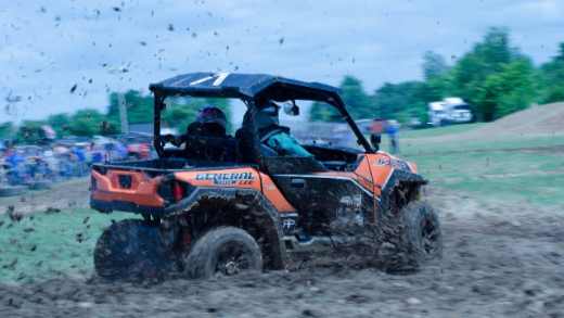 Men riding a Polaris General through the mud-1