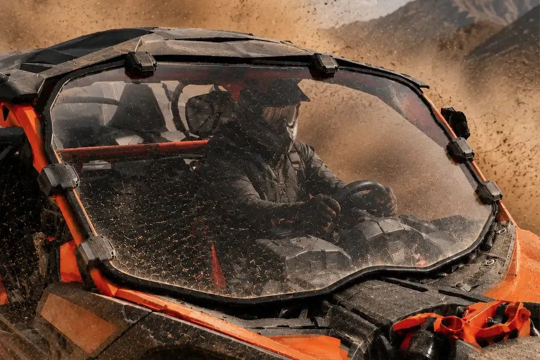 UTV windshield protecting driver on muddy off-road trail